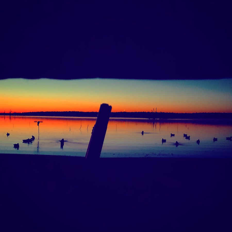 Sunrise burning over a flooded Kansas field with decoys on the water