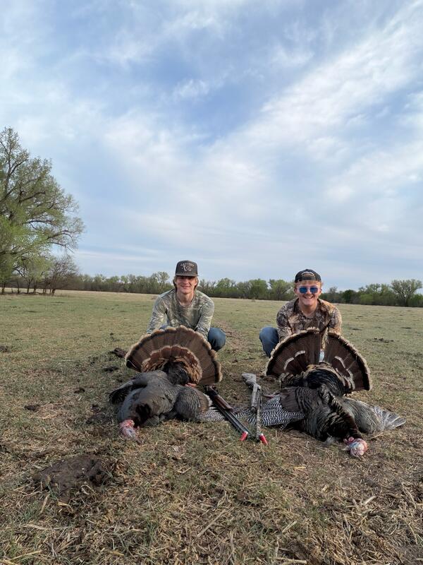 Two hunters with a pair of spring gobblers in a Kansas pasture