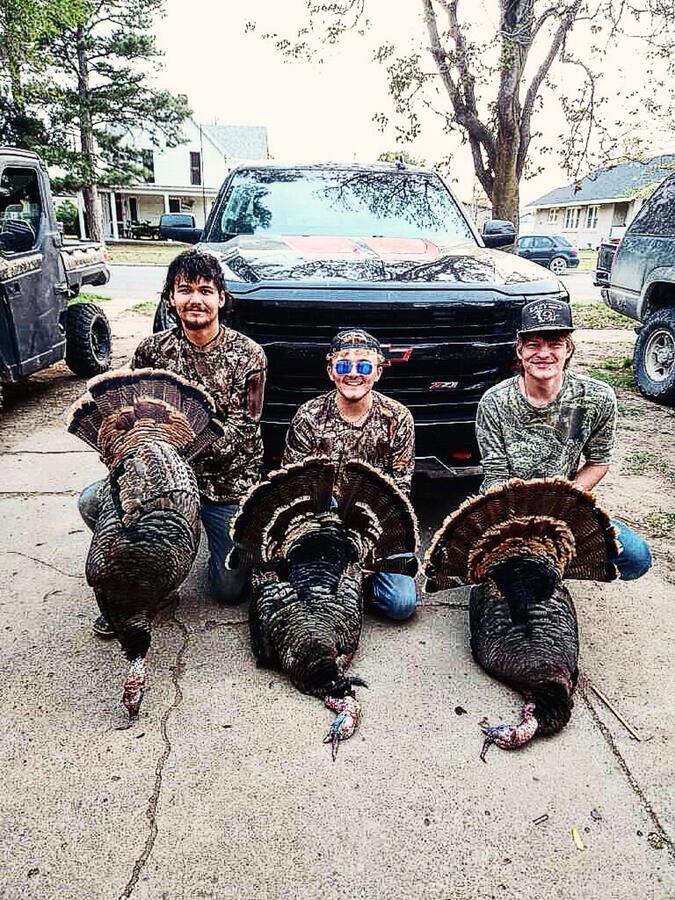 Three hunters with three Kansas gobblers at the truck